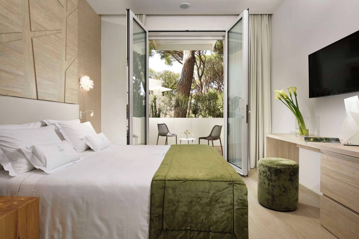 A modern hotel room with a bed, a desk, and a TV.