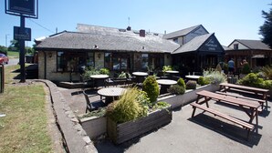 Un restaurante con terraza, que incluye mesas y bancos, y un letrero que indica que se llama 'The Waterloo Cross'.