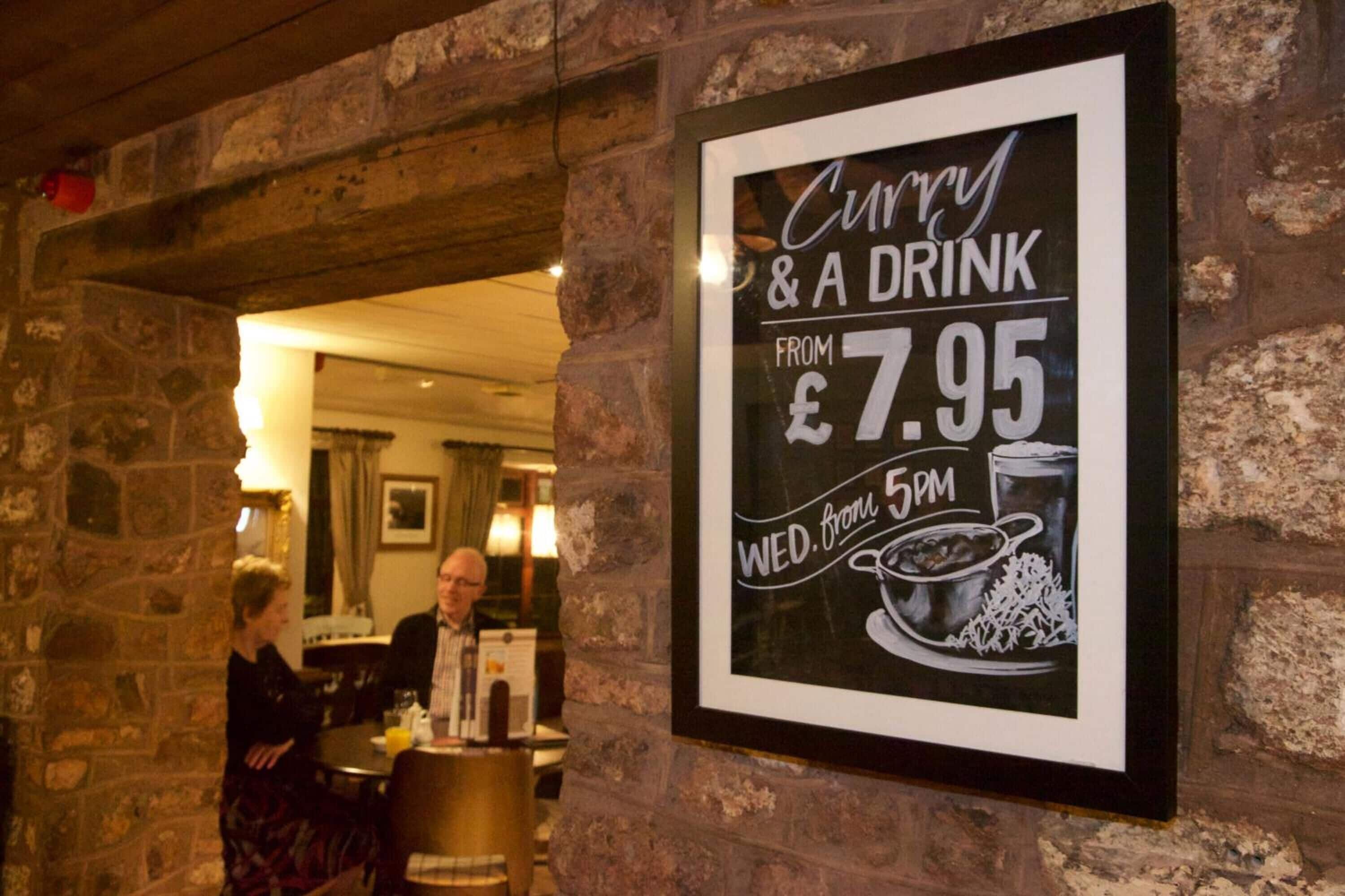 A sign advertising curry and a drink from 7.95 on Wednesdays from 5 PM.