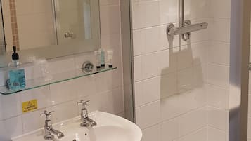 A bathroom with a white sink, a glass shower enclosure, and a mirror with lights.