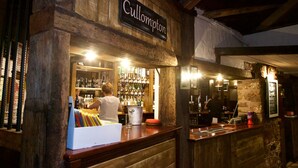Un bar con interior de madera, un letrero que dice "Cullompton" y estantes llenos de botellas.