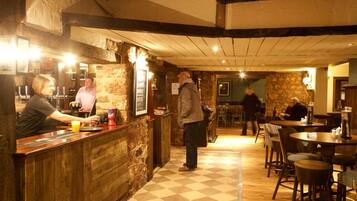 A restaurant with a wooden counter, stone walls, and checkered flooring.