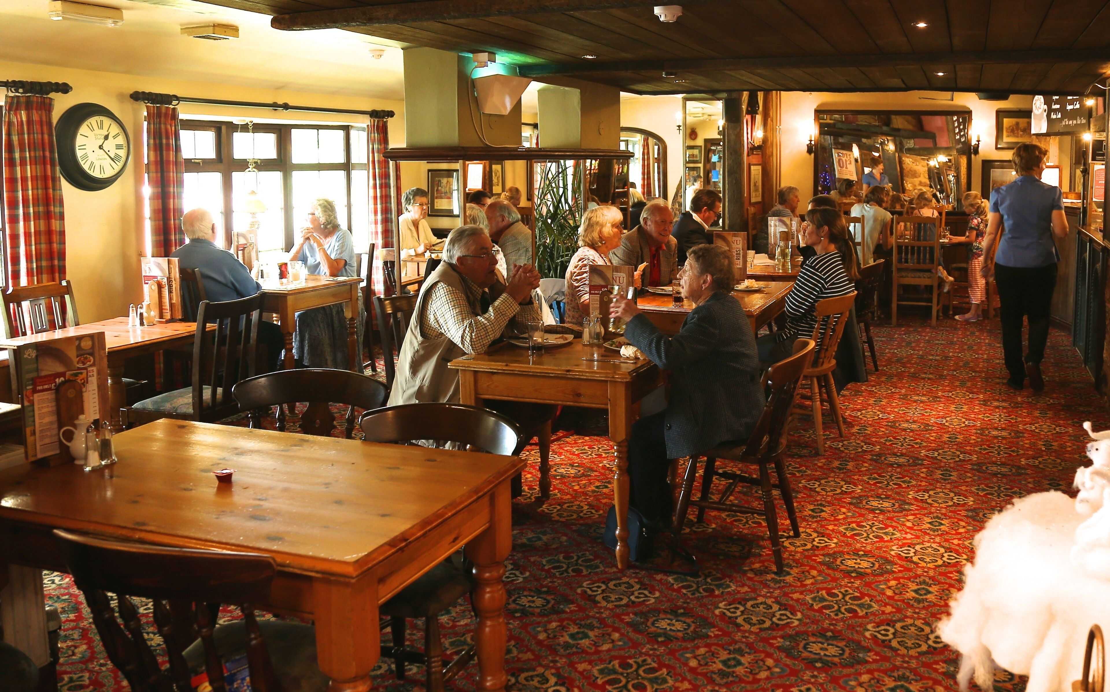 Ein traditionelles Gasthaus mit Holzmöbeln, einem gemusterten Teppich und einer Uhr an der Wand.