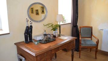 Een houten bureau met een spiegel, een lamp en een stoel in een kamer met een radiator en een raam met gordijnen.