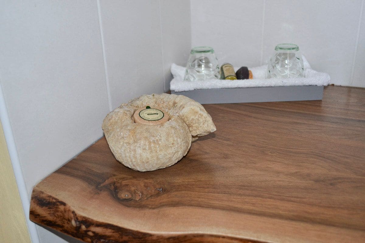 A wooden table with a decorative item and a small box containing two glass bottles and a bottle of lotion.