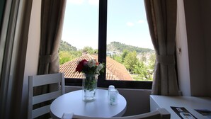 A room with a table, a chair, a vase with flowers, and a window with curtains. - Hotel Orestiada (Velabisht)