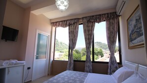 A bedroom with a bed, a dresser, a television, and a window with curtains. - Hotel Orestiada (Velabisht)