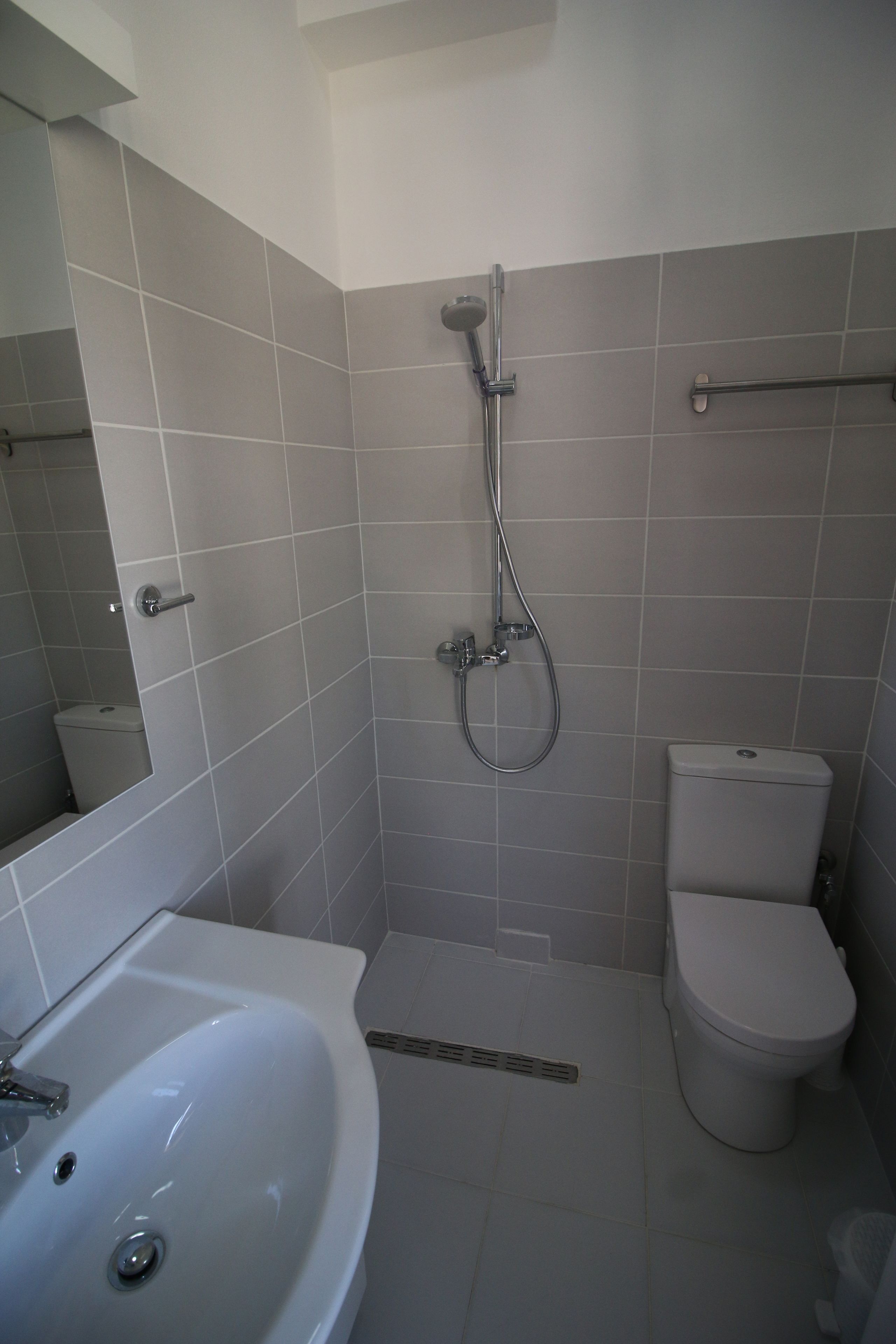 Un baño con lavamanos, inodoro y ducha blancos.