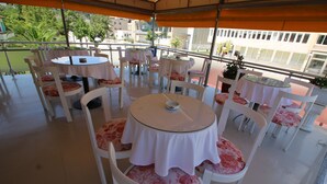 A terrace with round tables and white chairs, covered by an orange canopy. - Hotel Orestiada (Velabisht)