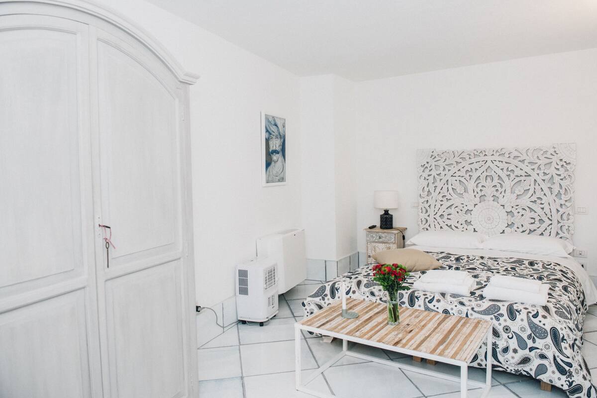Une chambre à coucher avec un lit, une table de chevet, une lampe et un radiateur.