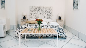 A neatly arranged bedroom with a patterned bedspread, a bedside table with a lamp, and a decorative headboard. - B&B L'Ambasciata (Gaeta)