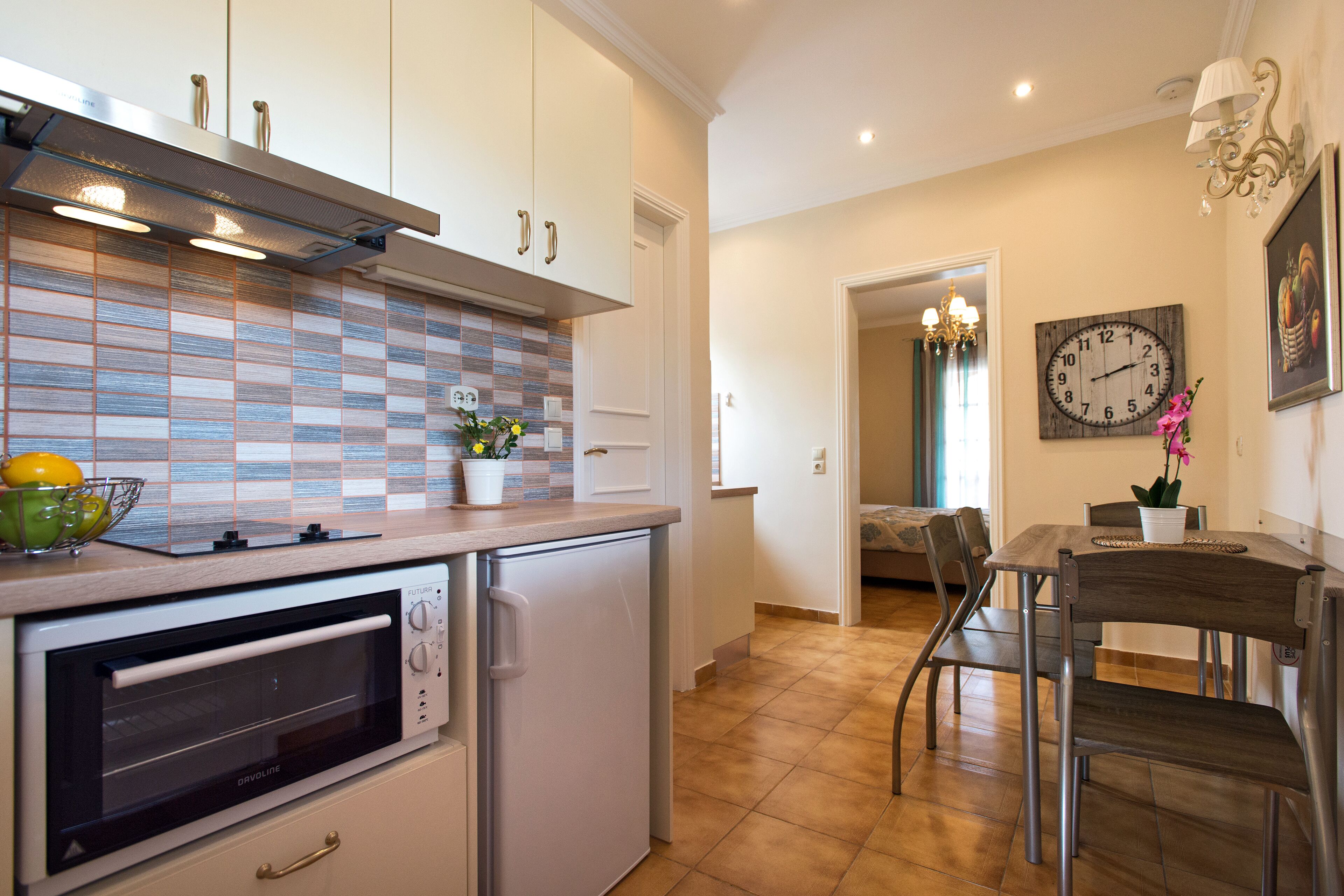 Eine moderne Küche mit Backofen, kleinem Kühlschrank und gefliestem Spritzschutz.