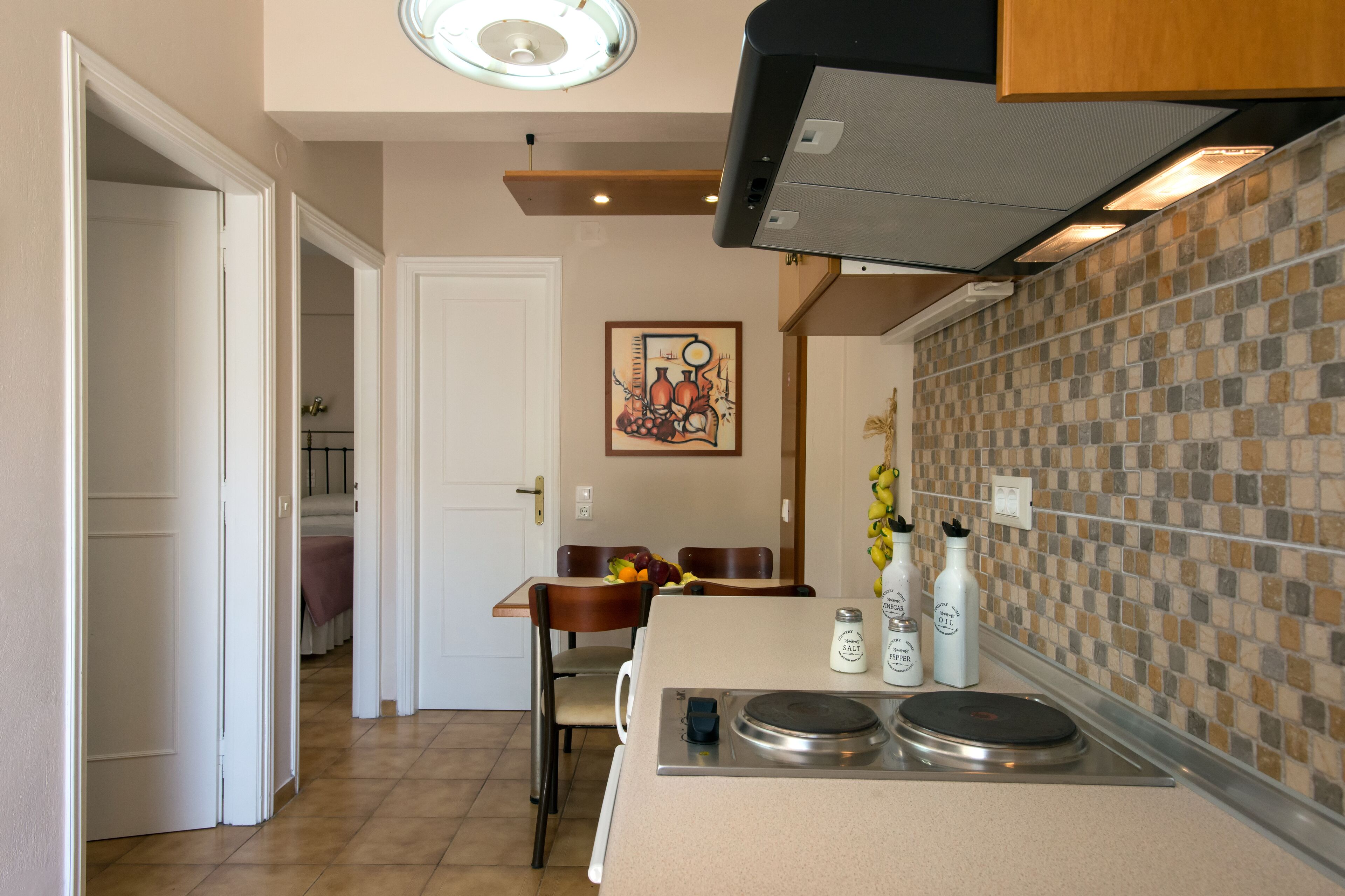 A modern kitchen with a central island, a dining area with a table and chairs, and a tiled backsplash.