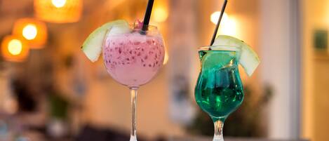 Two drinks on a table with a blurred background of lights.