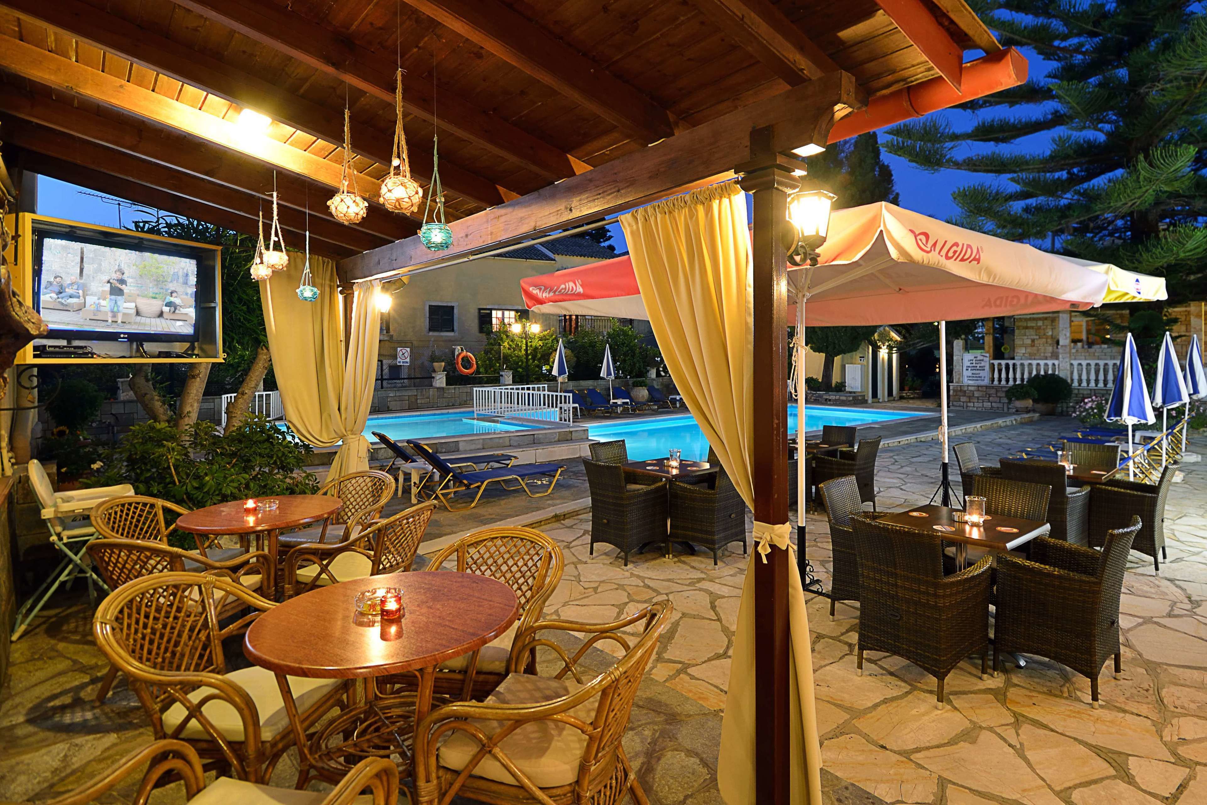 Un patio al aire libre con mobiliario de mimbre, una piscina y una zona de estar techada con sombrillas.