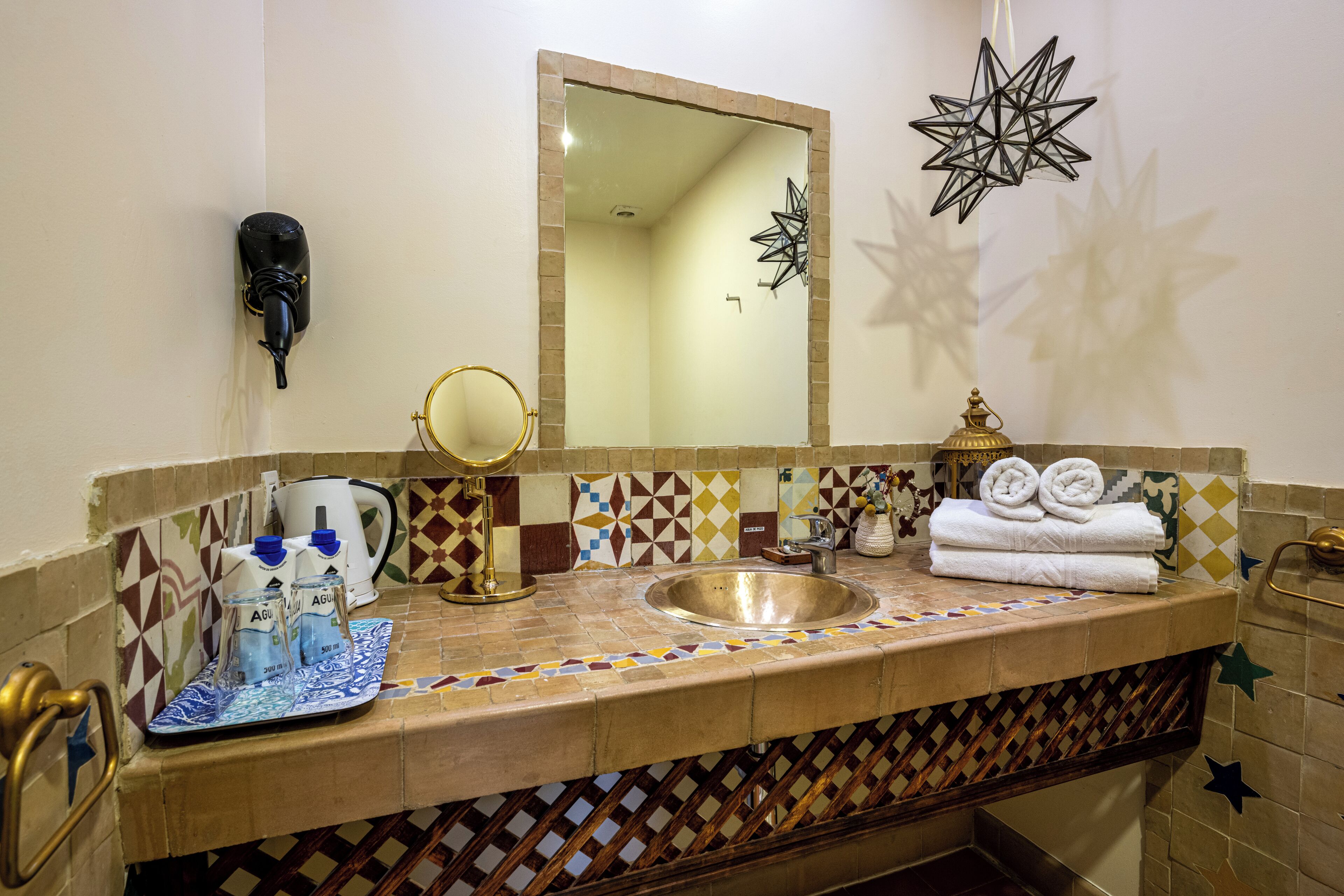 A bathroom with a sink, mirror, towel rack, and decorative star-shaped lights.