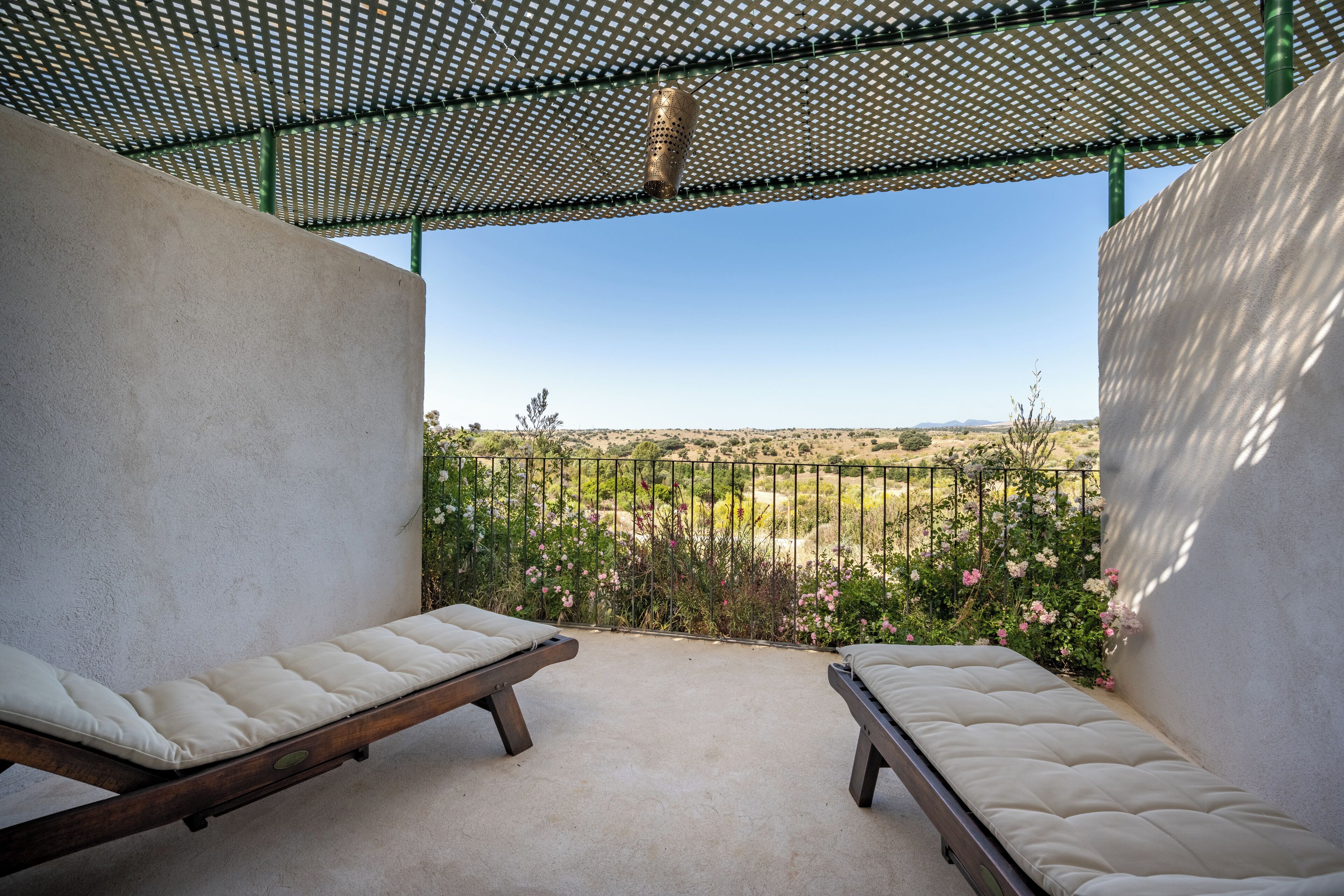 Un balcon avec deux lits en bois et une vue sur un paysage désertique.
