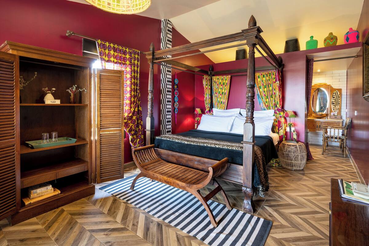 A bedroom with a four-poster bed, wooden furniture, and a herringbone floor pattern.