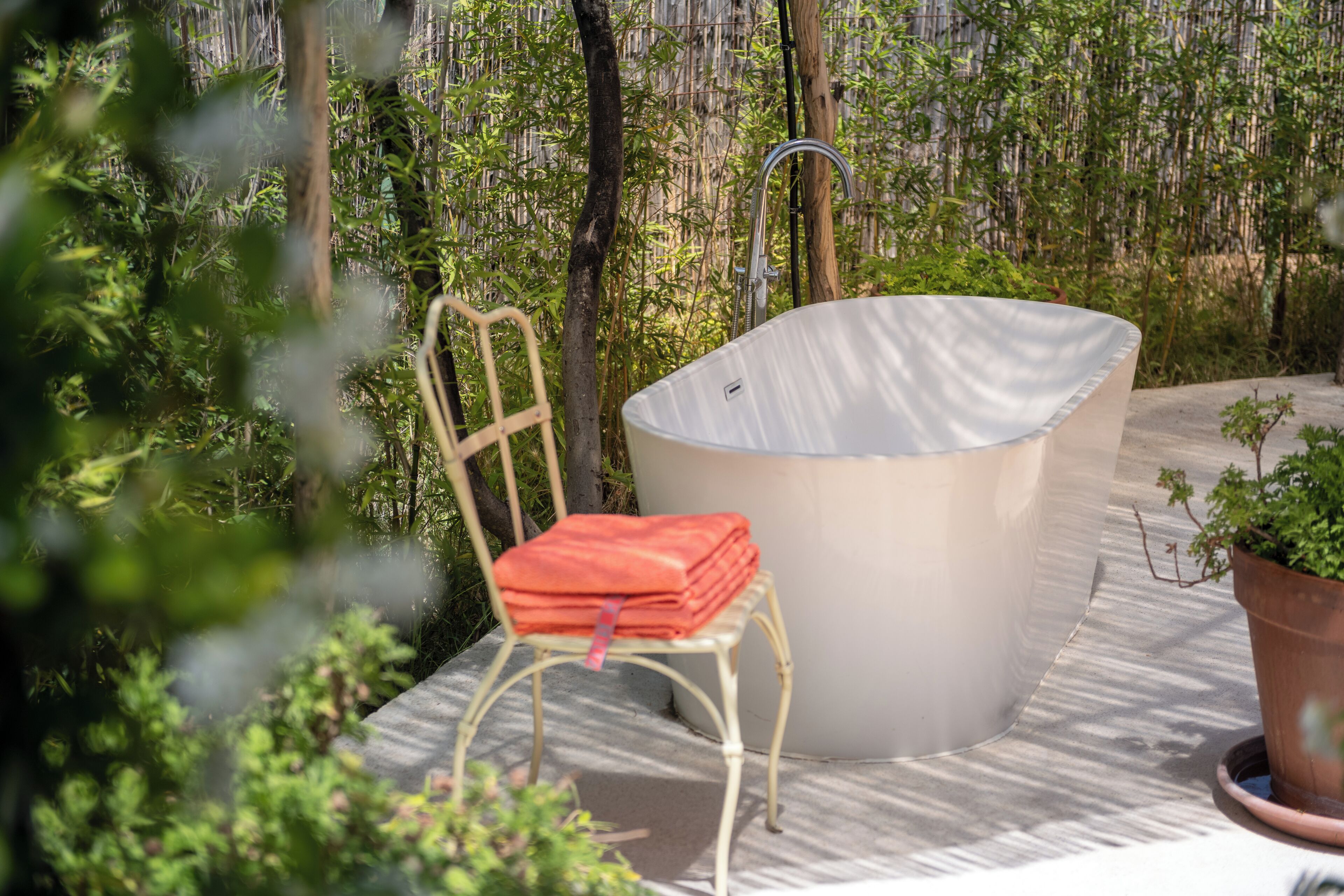 Zona de spa con una bañera de hidromasaje, una silla y una planta en maceta.