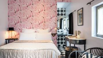 Un dormitorio con cama, mesita de noche, silla, pequeña mesa y espejo.