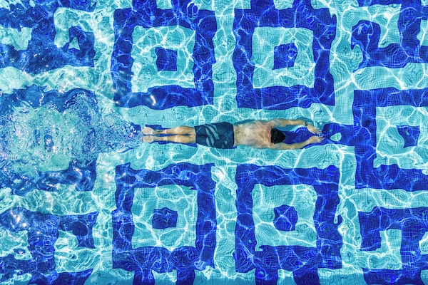 Una piscina al aire libre, sombrillas, sillones reclinables de piscina