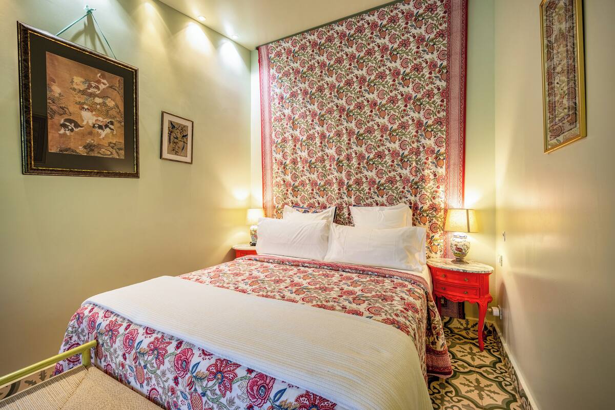 A hotel room with a large bed, a nightstand with a lamp, and a wall with framed artwork.