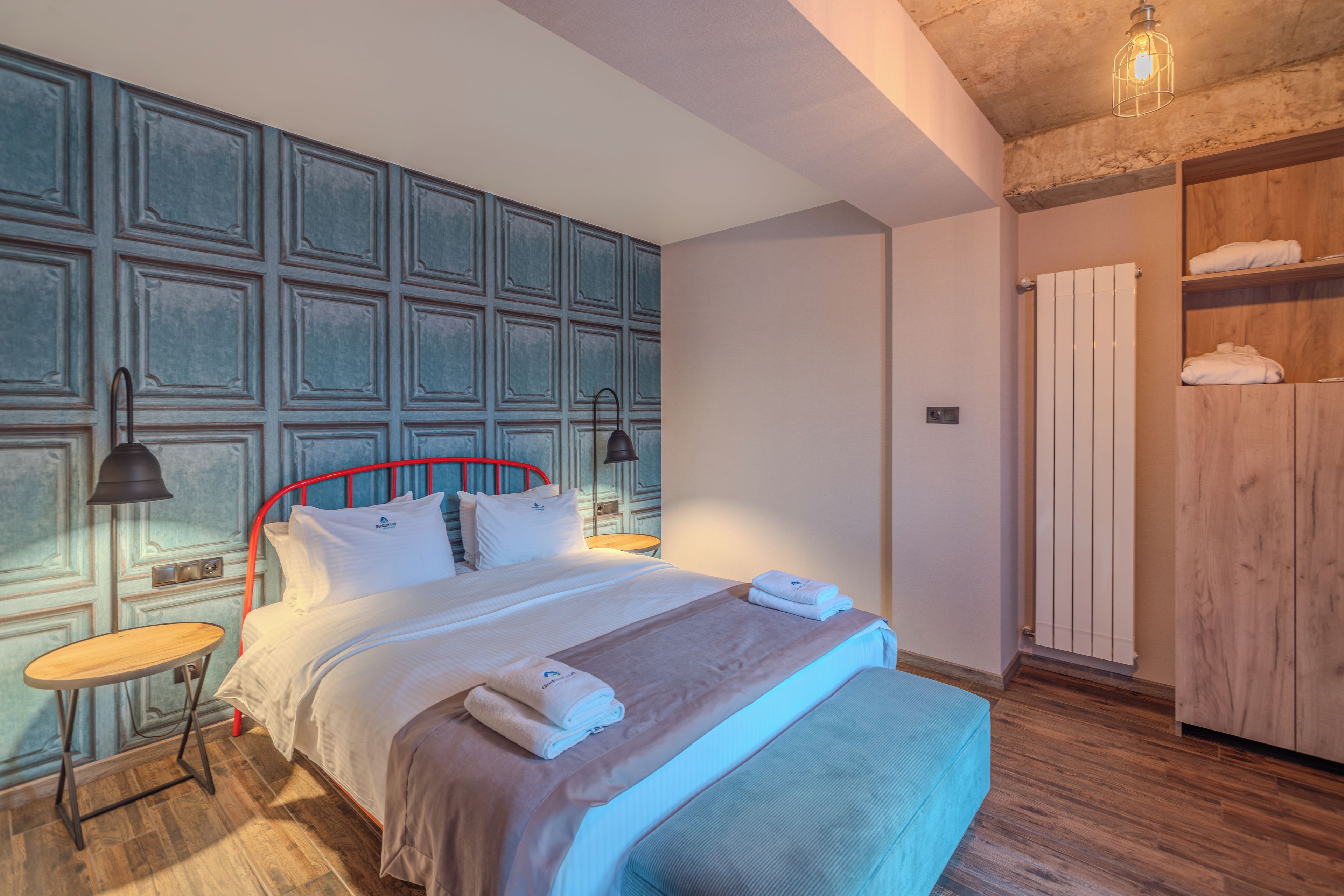Una habitación de hotel con una cama grande, un armario de madera y una mesita redonda.