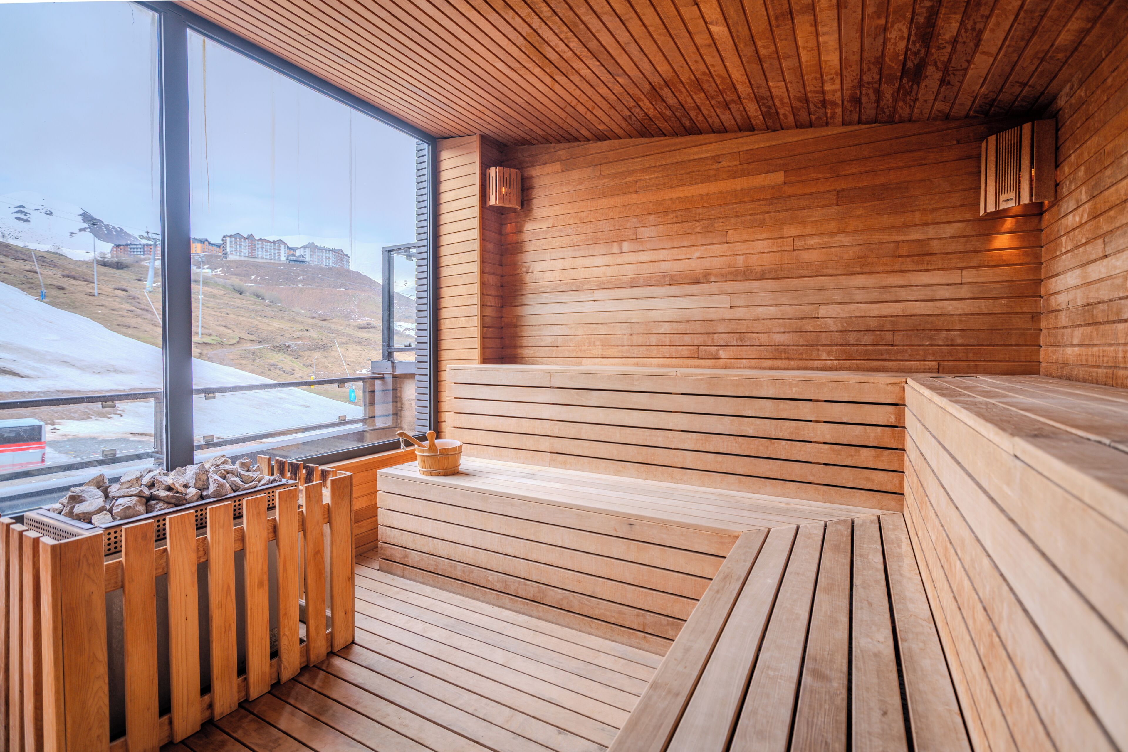 Un sauna en bois offrant une vue sur un paysage enneigé grâce à de grandes fenêtres.
