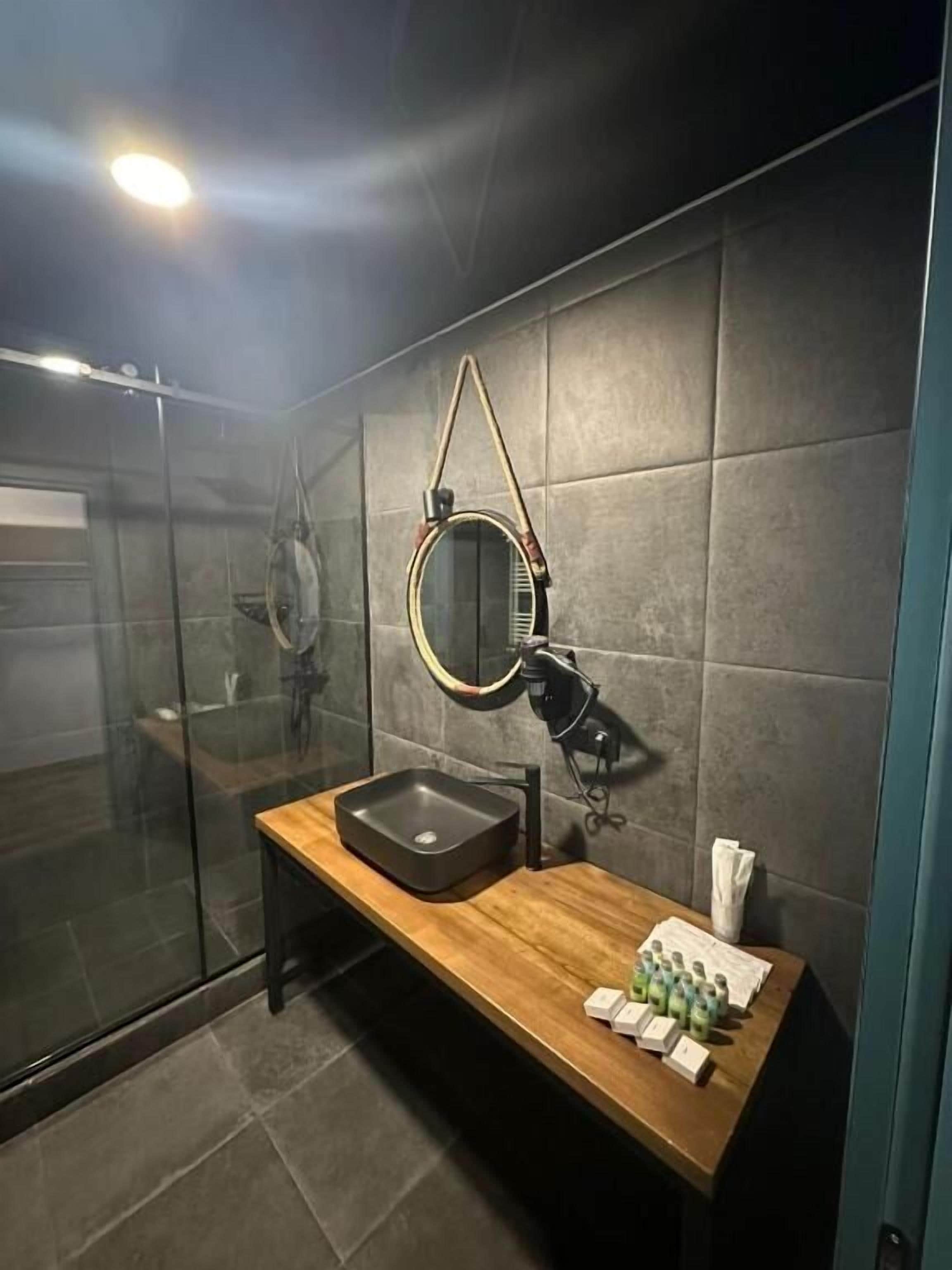Un baño moderno con cabina de ducha de vidrio, tocador de madera con lavabo y espejo.