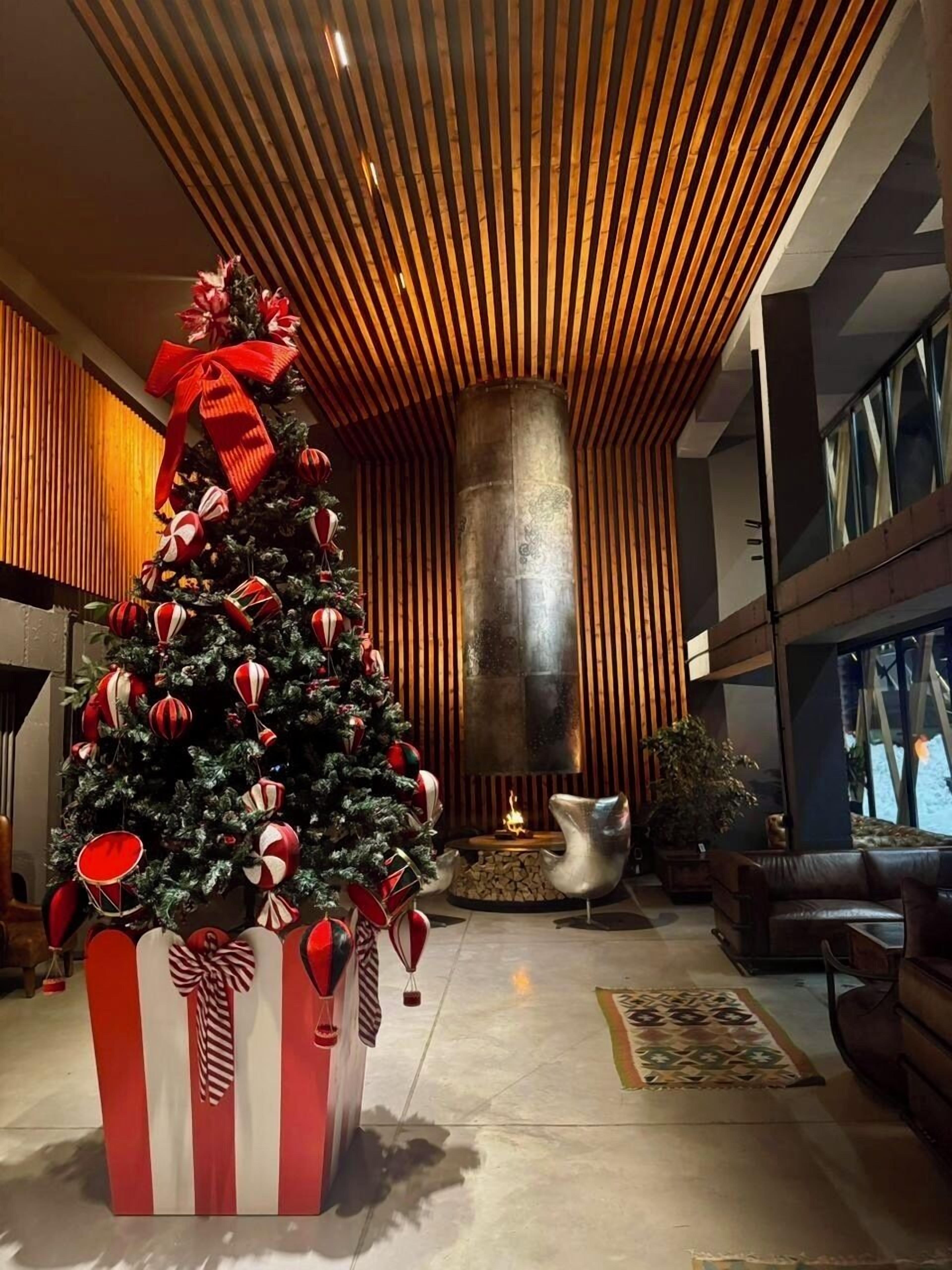 A modern lobby with a large Christmas tree, a fireplace, and contemporary furniture.