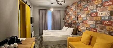 Een hotelkamer met een houten bureau, een gele bank, een bed en een wand versierd met scheepscentraters.