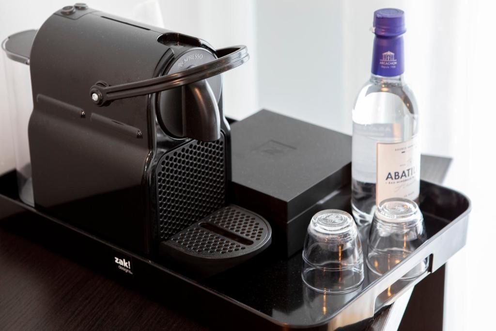 Una cafetera con una bandeja, una botella de Abatiil y dos vasos sobre una mesa.