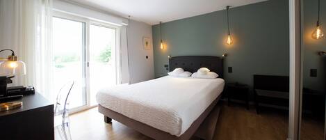 A modern bedroom with a large bed, a desk with a lamp, and a bench.