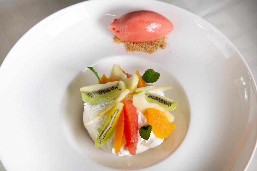 Eine Dessertplatte mit einer Kugel Eis und einer Obstplatte.