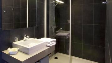 A modern bathroom with a glass-enclosed shower, a white sink, and a large mirror.