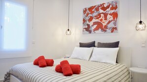 A hotel room with a bed, two bedside lamps, a window, and a wall art piece. - Unique Stylish Apt in Athens (Athens)