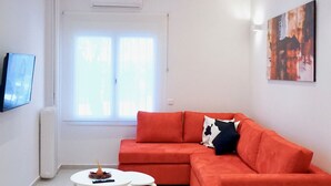 A modern living room with a red sectional sofa, a white coffee table, and a flat-screen TV mounted on the wall. - Unique Stylish Apt in Athens (Athens)