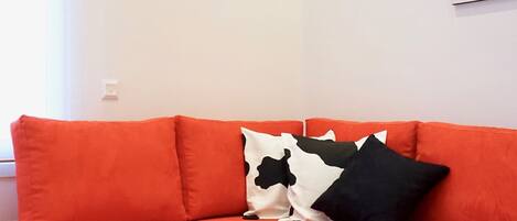 A modern living room with a red sectional sofa, a white coffee table with a decorative centerpiece, and a minimalist wall with a single artwork.