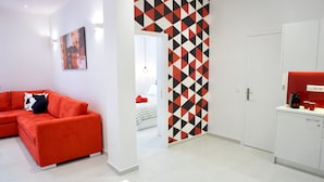 A modern apartment with a red sofa, a kitchen with white cabinets, and a geometric-patterned wall. - Unique Stylish Apt in Athens (Athens)