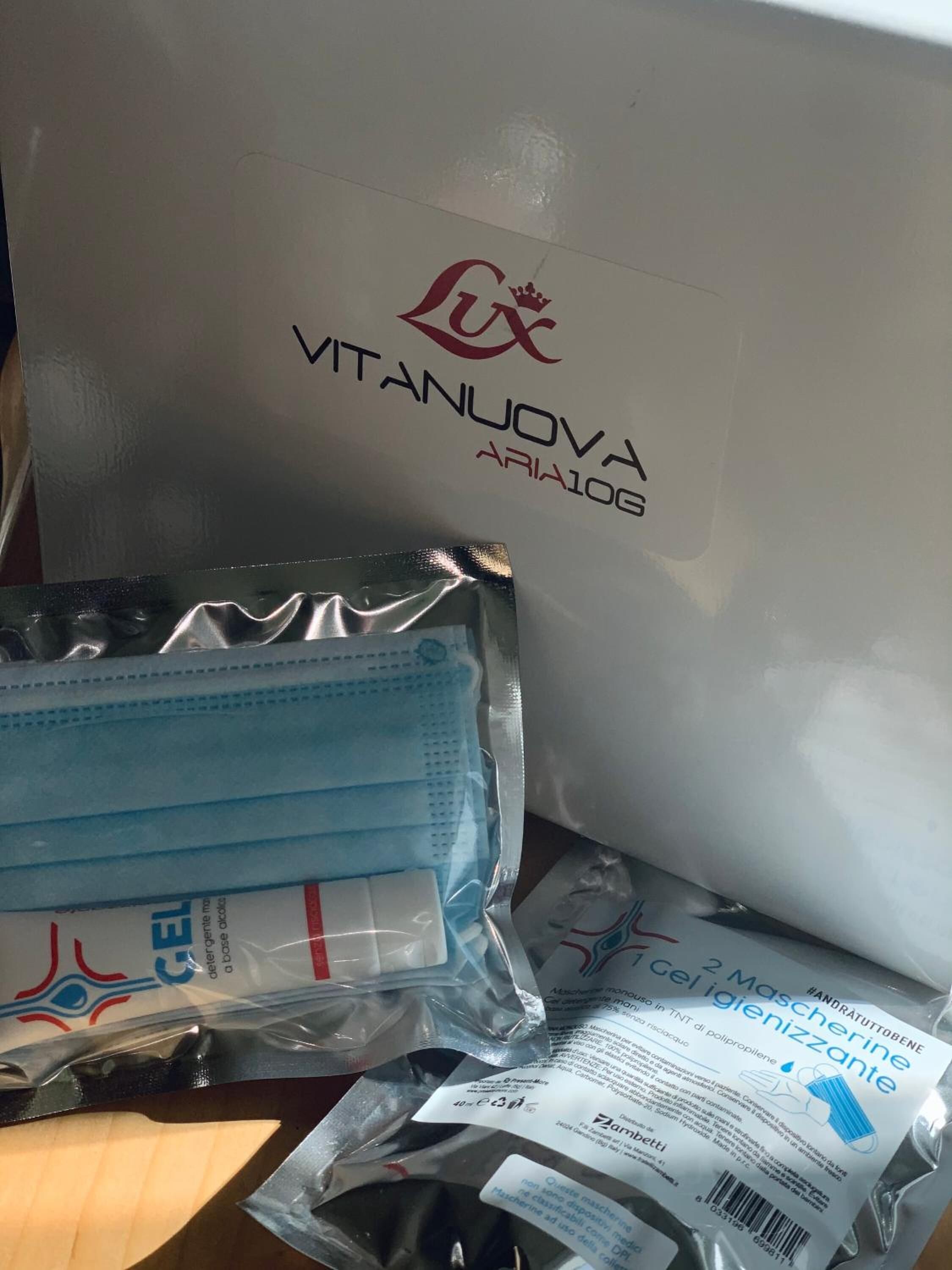 A white box with 'VITANUOVA ARIA10G' and a logo, alongside a plastic bag of blue surgical masks and a package of hand sanitizer.