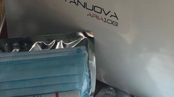 A white box with 'VITANUOVA ARIA10G' and a logo, alongside a plastic bag of blue surgical masks and a package of hand sanitizer.