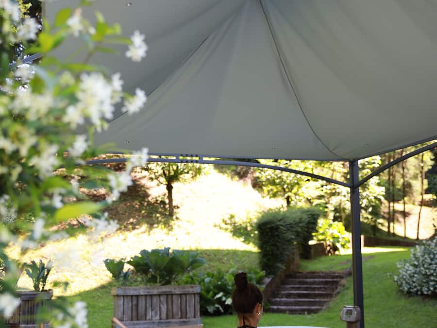 A hot tub under a tent with a table and drinks in the foreground.