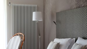 A hotel room with a bed, a chair, a lamp, and a radiator. - Garden Hotel Ristorante (Fino del Monte)