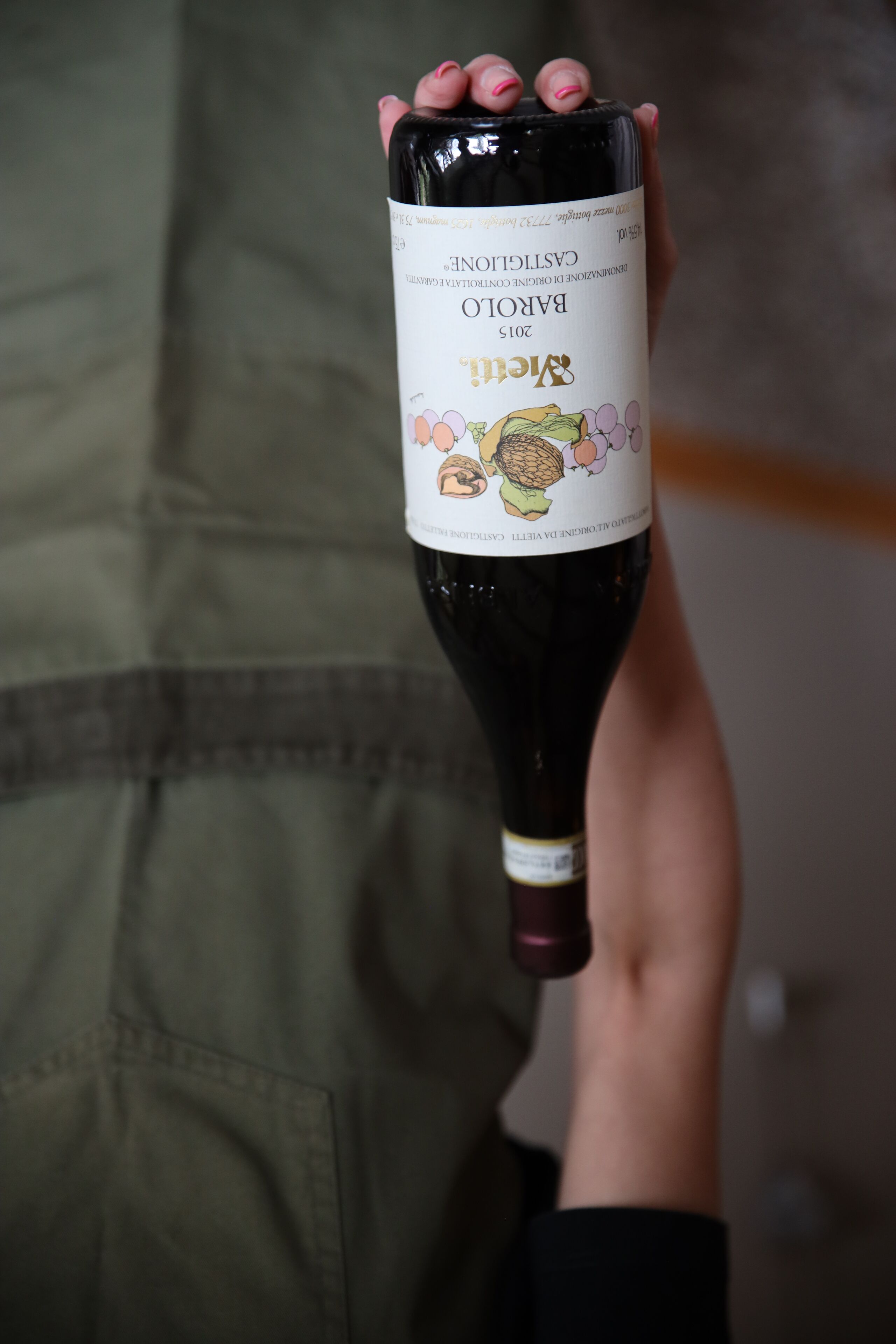 A hand holding a bottle of wine with a label that reads "Barolo 2015".