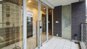 A modern building entrance with glass doors, a metal railing, and a tiled floor. - THE BEDROOM Daimyo (Fukuoka)