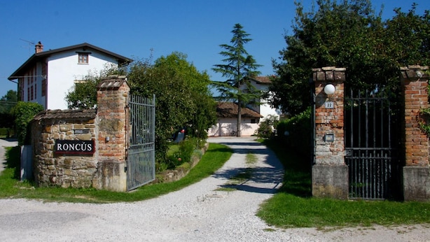 Propiedad rural con camino de grava que conduce a una entrada con portón.