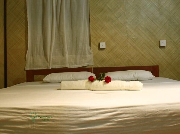 A neatly made bed with a white bedspread and pillows, a white towel with red flowers, and a wooden headboard. - Thick forest sigiriya (Sigiriya)