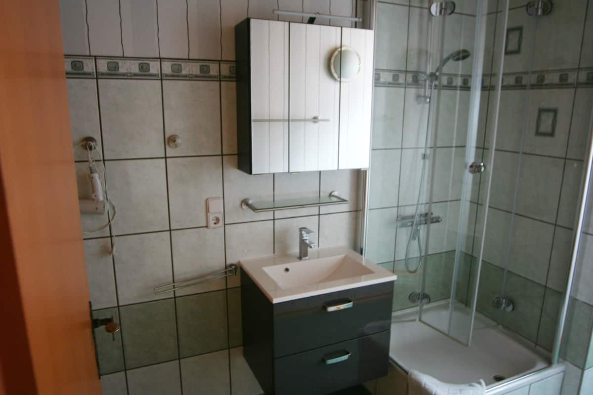 Ein Badezimmer mit Waschbecken, Spiegel, Schrank und Dusche.