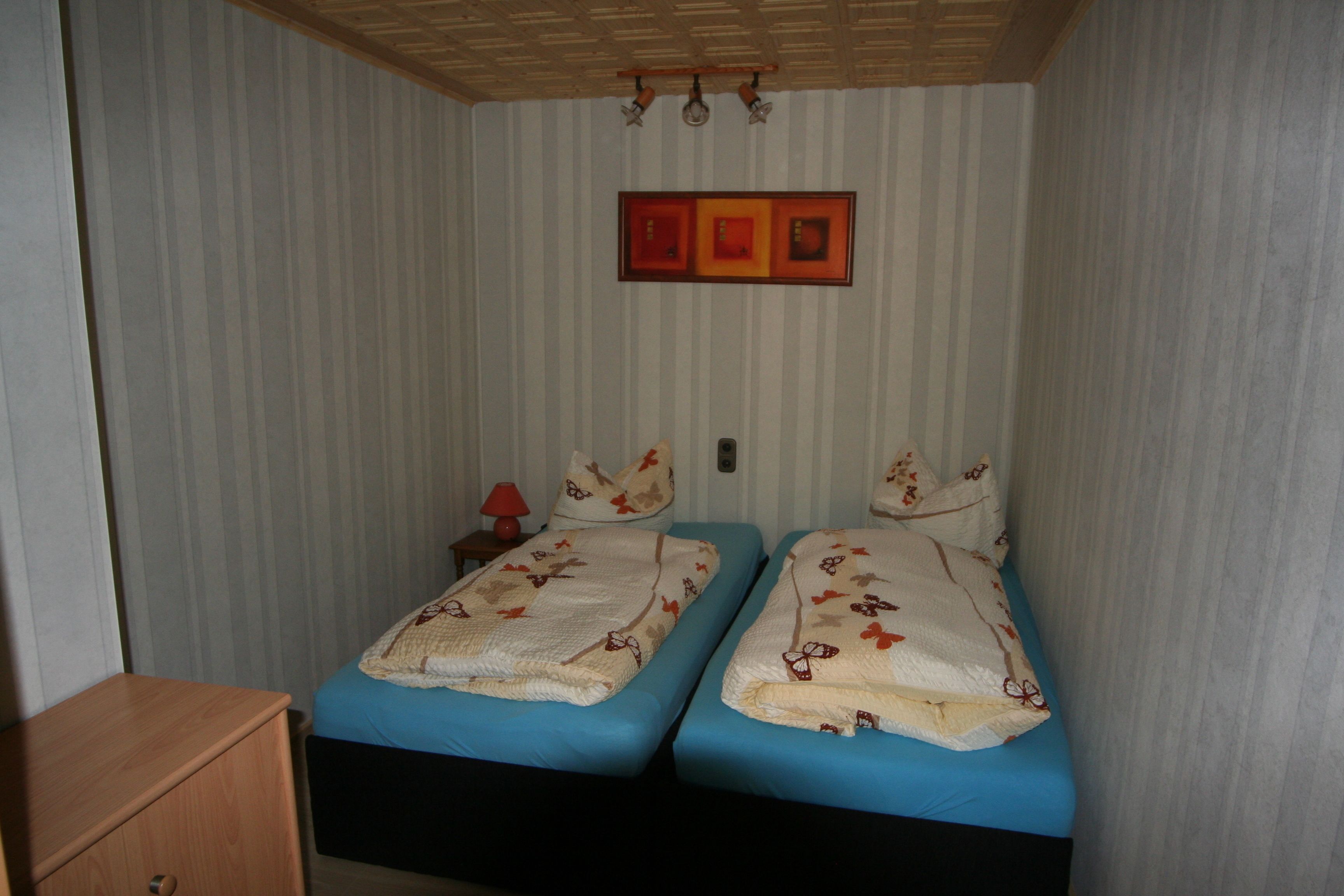 Une chambre avec deux lits, un papier peint à rayures et un plafond en bois.