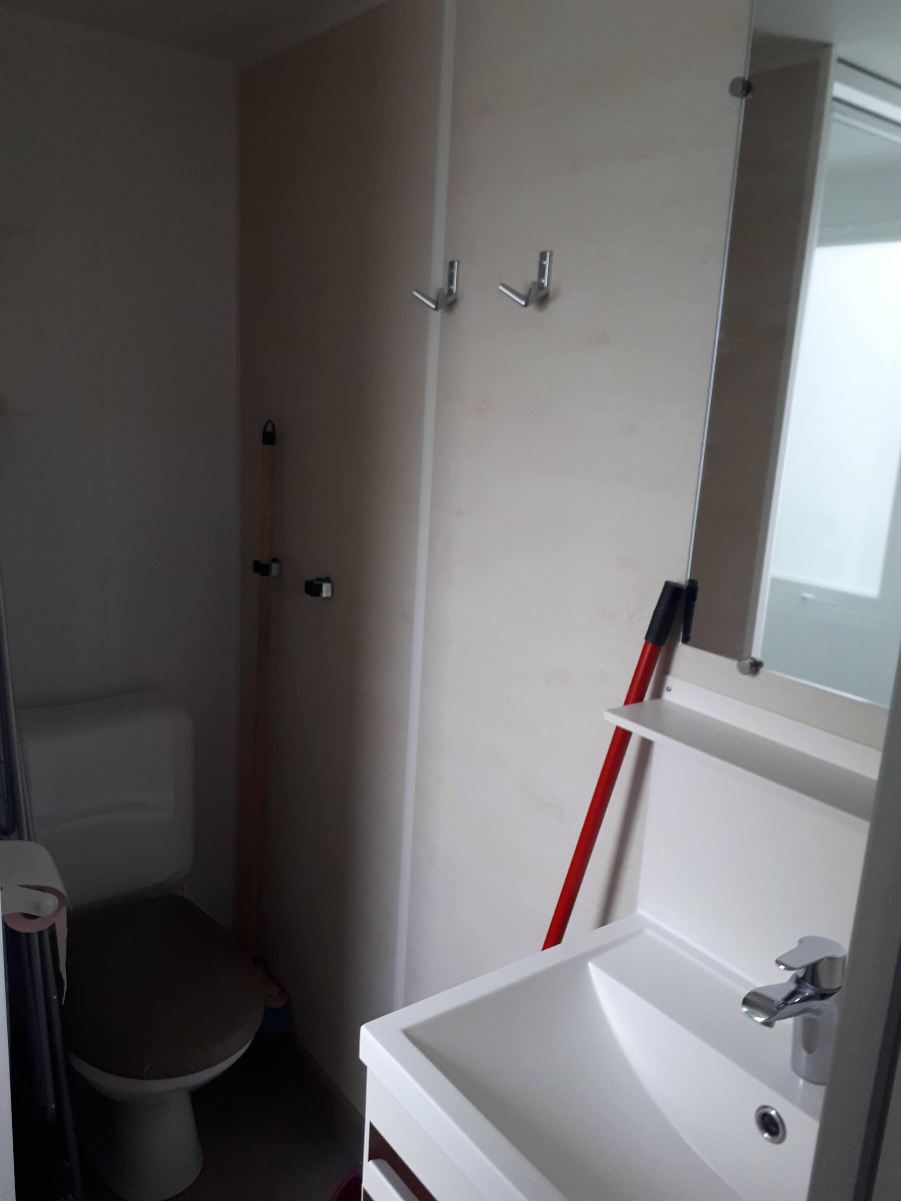 A small bathroom with a toilet, a sink, and a mirror.